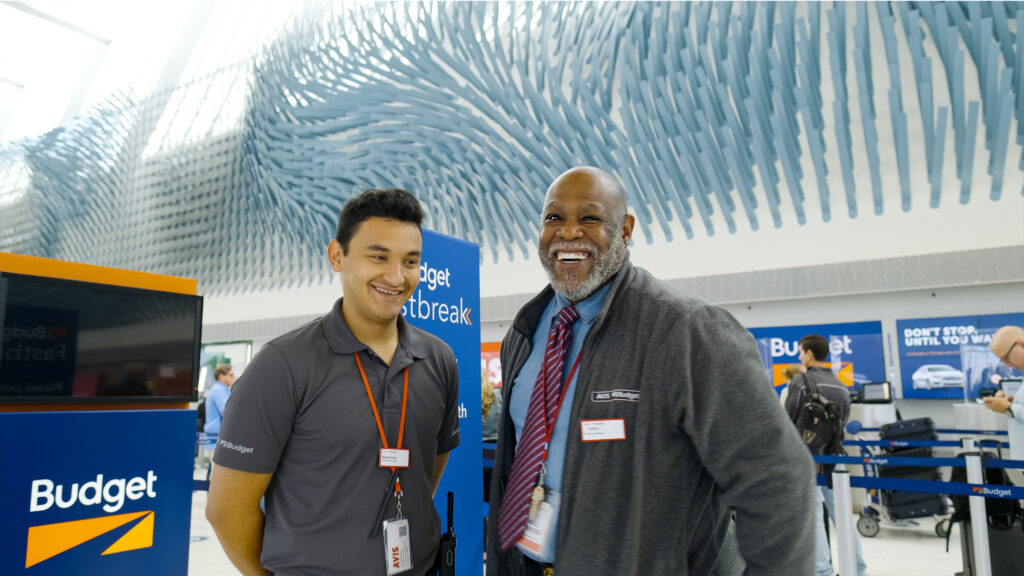 Two men standing in front of Budget signs at an airport
